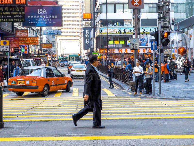 HONGKONG, CHINA - December 9 2016: Business man walking across the crosswalk on the road with city background. Hong Kong royalty free stock photos HONGKONG, CHINA - December 9 2016: Business man walking across the crosswalk on the road with city background. Hong Kong royalty free stock photos
