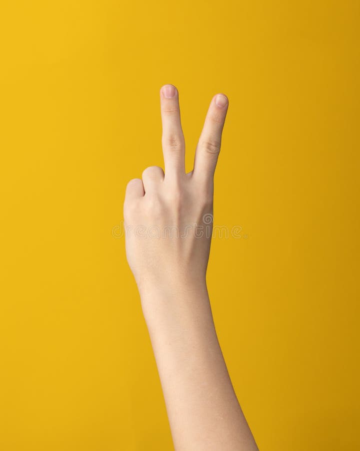 Honhandsgesten visar två fingrar och mitt på gul arkivbild