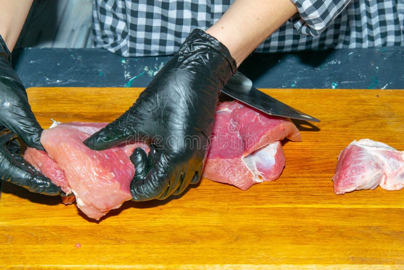 Honhandskar i svarta handskar i bitar av juicer av fläskkött
