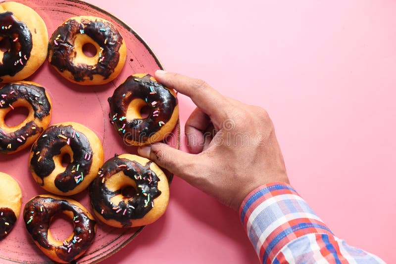 Hoogengel : man pakt chocoladedonuts uit van plaat royalty-vrije stock afbeelding