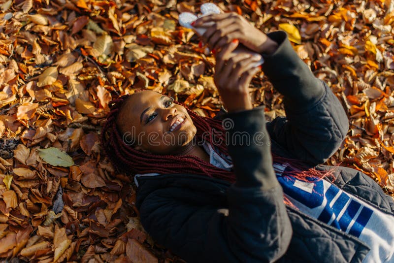 Hoogste mening bij het mooie aantrekkelijke Afrikaanse meisje met rood haar en mooie glimlach die, en op texting doorbladeren bab stock afbeelding Hoogste mening bij het mooie aantrekkelijke Afrikaanse meisje met rood haar en mooie glimlach die, en op texting doorbladeren bab stock afbeelding