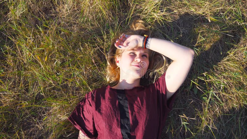 Hoogste mening die van mooi meisje met blondehaar op groen gras bij weide en het dromen liggen Het jonge vrouw ontspannen bij stock videobeelden Hoogste mening die van mooi meisje met blondehaar op groen gras bij weide en het dromen liggen Het jonge vrouw ontspannen bij stock videobeelden