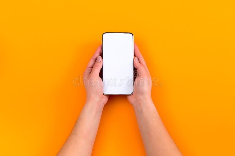 Hoogste mening van een vrouwenhand die telefoon op oranje achtergrond met behulp van stock foto Hoogste mening van een vrouwenhand die telefoon op oranje achtergrond met behulp van stock foto