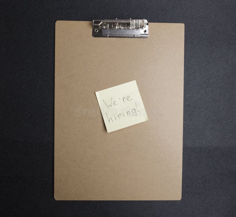 Hoogste mening van klembord en gele sticker met woordhand die ‚wij huren ‚schrijven Concept het zoeken naar werknemers stock foto Hoogste mening van klembord en gele sticker met woordhand die ‚wij huren ‚schrijven Concept het zoeken naar werknemers stock foto