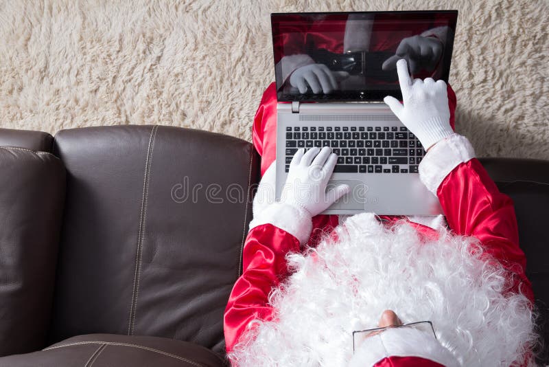 Hoogste mening van Santa Claus-zitting in laag gebruikend laptop en richtend op het scherm stock foto's Hoogste mening van Santa Claus-zitting in laag gebruikend laptop en richtend op het scherm stock foto's