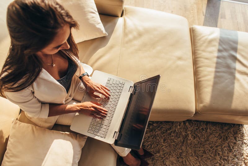 Hoogste mening van vrouwenzitting op een bank met laptop bij haar overlapping het typen op toetsenbord thuis royalty-vrije stock afbeeldingen Hoogste mening van vrouwenzitting op een bank met laptop bij haar overlapping het typen op toetsenbord thuis royalty-vrije stock afbeeldingen