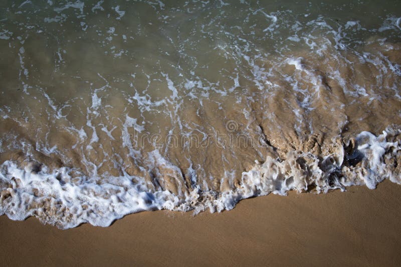 Hoogste menings dicht omhooggaand detail van de motieschuim van de zeewatergolf op zandige strandtextuur als achtergrond stock foto Hoogste menings dicht omhooggaand detail van de motieschuim van de zeewatergolf op zandige strandtextuur als achtergrond stock foto