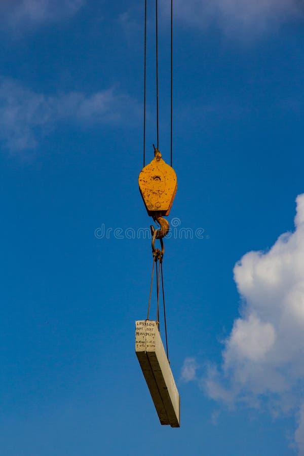 The hook of a construction crane with a suspended load on the background of the sky