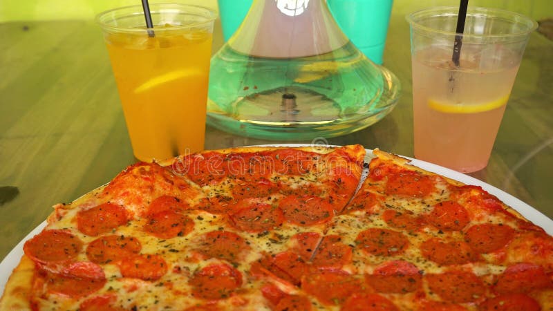 Hookah hierve al fondo de una pizza de pepperoni caliente y limonada fresca en un café callejero metrajes