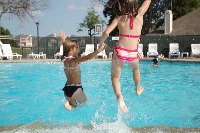 Two friends hold hands and jump into the pool together. Summer is here and school is out. Two friends hold hands and jump into the pool together. Summer is here and school is out.