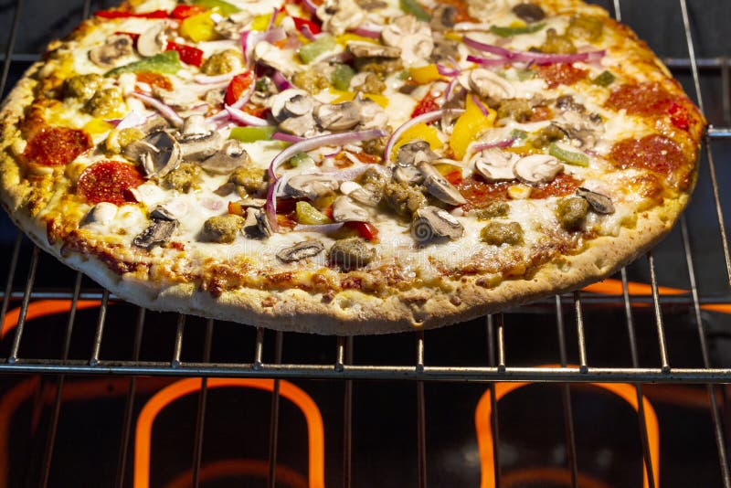 Horizontal photo of fresh pizza baking in electric oven with burners glowing hot underneath oven rack. Horizontal photo of fresh pizza baking in electric oven with burners glowing hot underneath oven rack