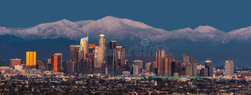 Horizon de van de binnenstad van Los Angeles met sneeuw afgedekte bergen erachter bij schemering