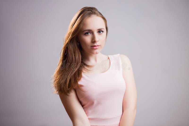 Horizontaal portret van mooi jong studentenmeisje die in roze kleding camera bekijken een grijze achtergrond stock afbeeldingen Horizontaal portret van mooi jong studentenmeisje die in roze kleding camera bekijken een grijze achtergrond stock afbeeldingen