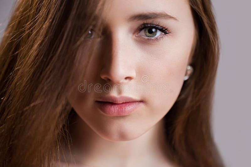 Horizontal closeup portrait of a beautiful young woman with clean skin, long eyelashes and natural beauty, fresh face. Green eyes, charming girl`s look into the camera