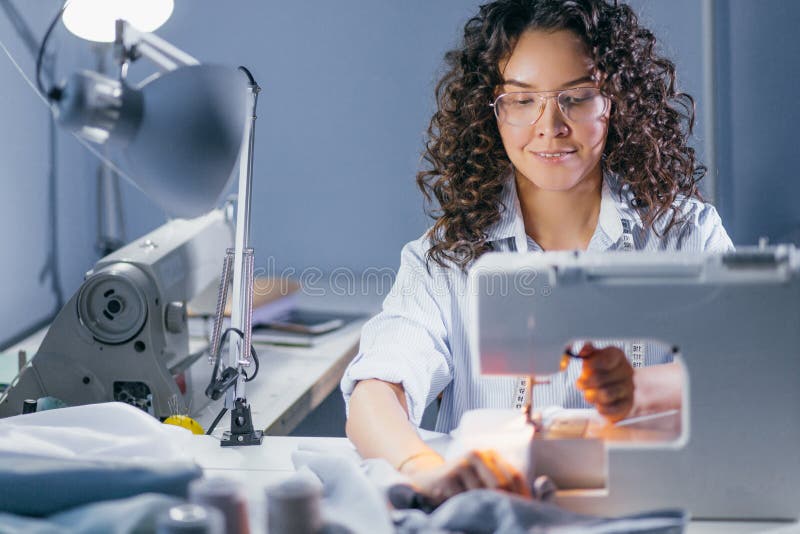 Photo of dressmaker sewing fabric on stitching machine stock photography
