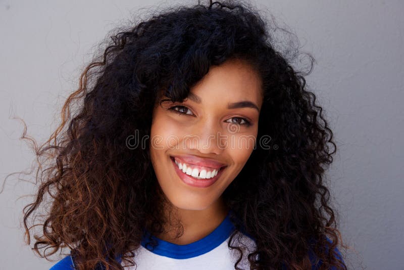 Horizontal portrait of smiling young black woman against gray wall