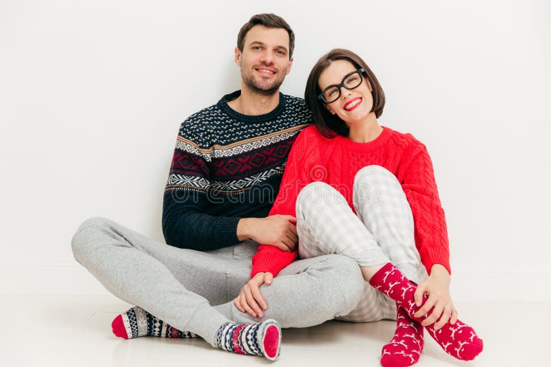 Horizontal shot of happy lovers sit together against white studio background, wear casual clothes, enjoy leisure time at home. Ad stock photography Horizontal shot of happy lovers sit together against white studio background, wear casual clothes, enjoy leisure time at home. Ad stock photography