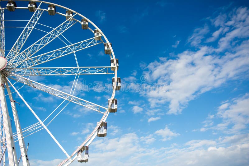 Horizontal View of a White Ferris Wheel on Partially Cloudy Sky Stock