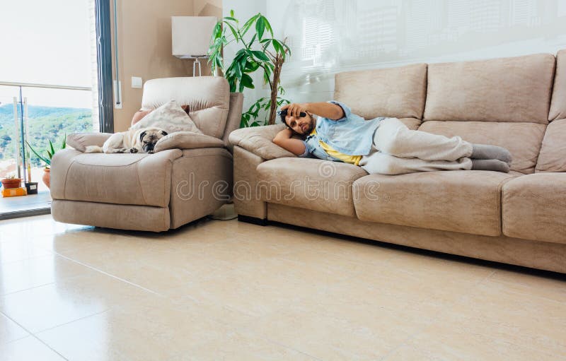 A horizontal shot of a male lying on the sofa and watching TV. A horizontal shot of a male lying on the sofa and watching TV