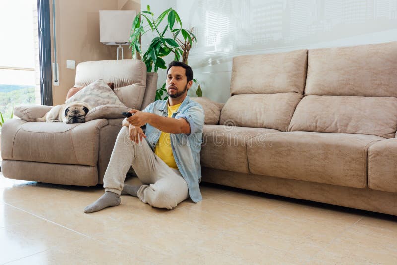 A horizontal shot of a male sitting on the floor and watching TV. A horizontal shot of a male sitting on the floor and watching TV