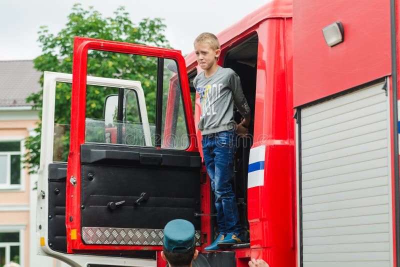 HORKI, BIELORUSSIA - 25 LUGLIO 2018: Il ragazzo guarda dall'automobile rossa di servizio di salvataggio 112 su una festa nel parc fotografie stock libere da diritti HORKI, BIELORUSSIA - 25 LUGLIO 2018: Il ragazzo guarda dall'automobile rossa di servizio di salvataggio 112 su una festa nel parc fotografie stock libere da diritti