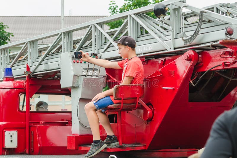 HORKI, BIELORUSSIA - 25 LUGLIO 2018: Un ragazzo prende un selfie su un servizio di salvataggio rosso dell'automobile 112 di una f fotografia stock libera da diritti HORKI, BIELORUSSIA - 25 LUGLIO 2018: Un ragazzo prende un selfie su un servizio di salvataggio rosso dell'automobile 112 di una f fotografia stock libera da diritti
