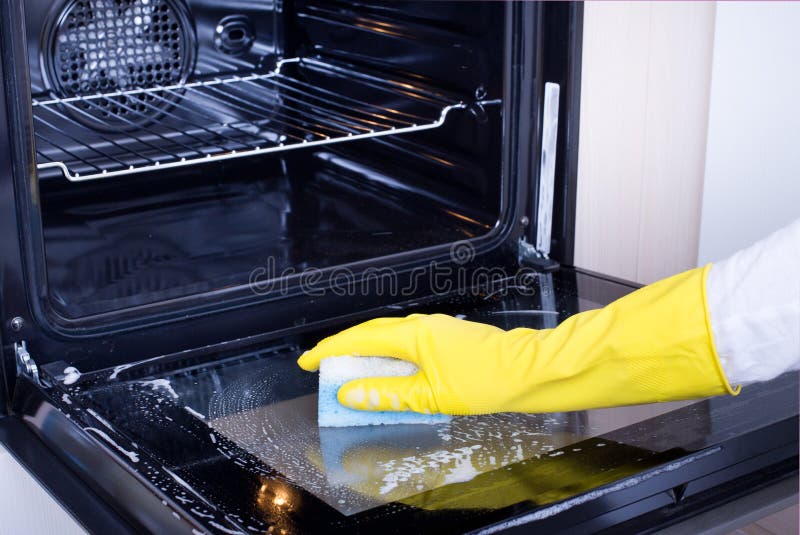 Mujer joven con guantes de limpieza de horno en la cocina. concepto de  servicio de limpieza