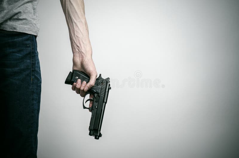 Horror and firearms topic: suicide with a gun on a gray background in the studio