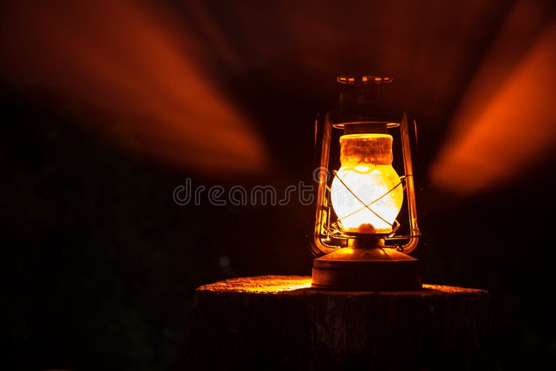 Horror Halloween concept. Burning old oil lamp in forest at night. Night scenery of a nightmare scene.