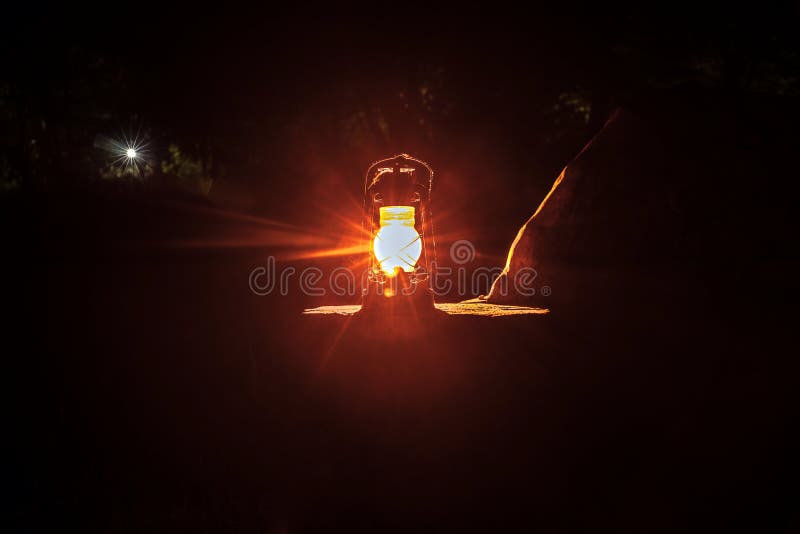 Horror Halloween concept. Burning old oil lamp in forest at night. Night scenery of a nightmare scene.