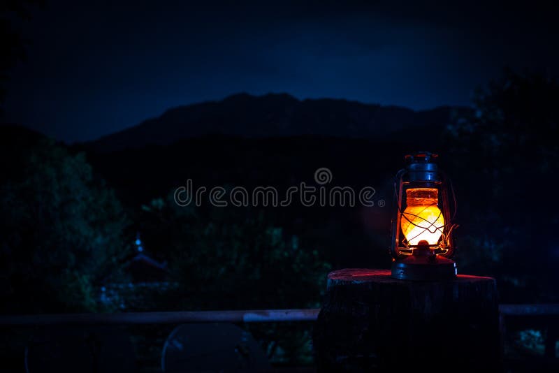 Horror Halloween concept. Burning old oil lamp in forest at night. Night scenery of a nightmare scene.