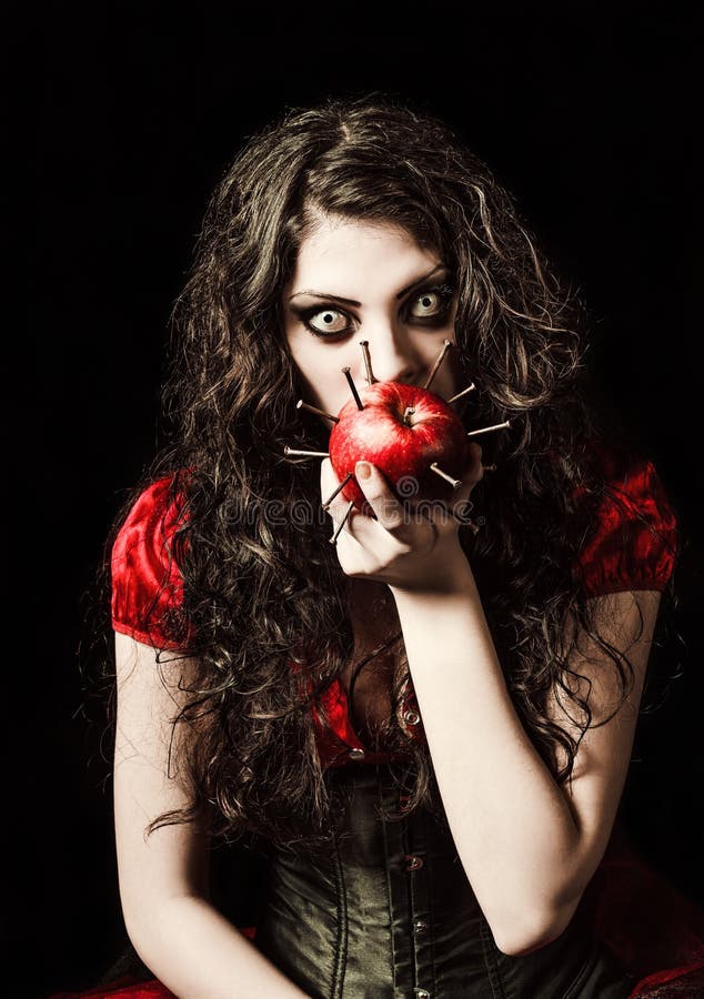 Horror shot: strange scary girl eats apple studded with nails stock image Horror shot: strange scary girl eats apple studded with nails stock image