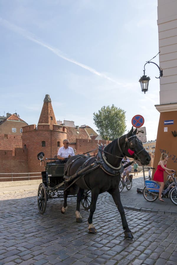 Horse carriage with tourists in the street with Warsaw Barbican in summer sunny day royalty free stock photography Horse carriage with tourists in the street with Warsaw Barbican in summer sunny day royalty free stock photography