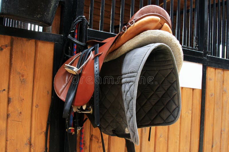 Inside of a horse stable with many rooms for horses and a close up of a saddle!