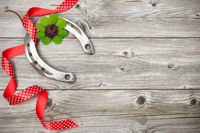 Holidays background with horseshoe, shamrock and red ribbon on old wooden