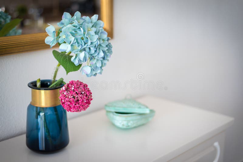 Hortenzia hidrangea flor azul claro en un jarrón azul sobre un armario con espejo en el fondo fotografía de archivo Hortenzia hidrangea flor azul claro en un jarrón azul sobre un armario con espejo en el fondo fotografía de archivo