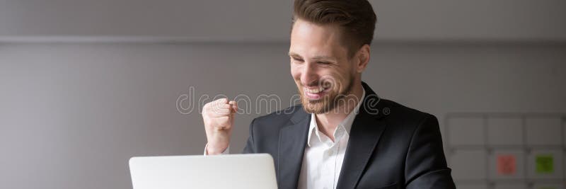 Horyzontalnej fotografii millennial biznesmen czuje szczęśliwego otrzymywającego dobre wieści online fotografia royalty free Horyzontalnej fotografii millennial biznesmen czuje szczęśliwego otrzymywającego dobre wieści online fotografia royalty free