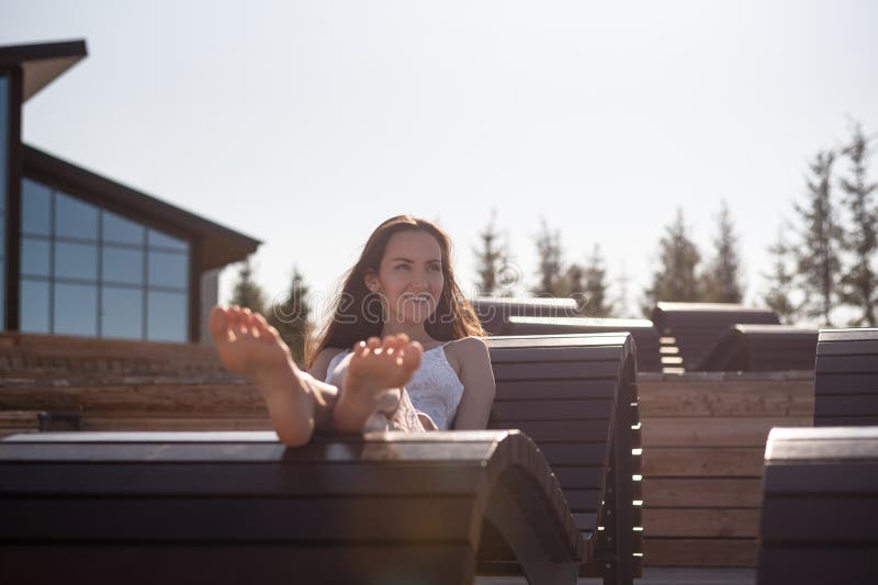Horyzontalny portret młoda kobieta w białym smokingowym lying on the beach na ono uśmiechać się i sunbed obraz stock Horyzontalny portret młoda kobieta w białym smokingowym lying on the beach na ono uśmiechać się i sunbed obraz stock