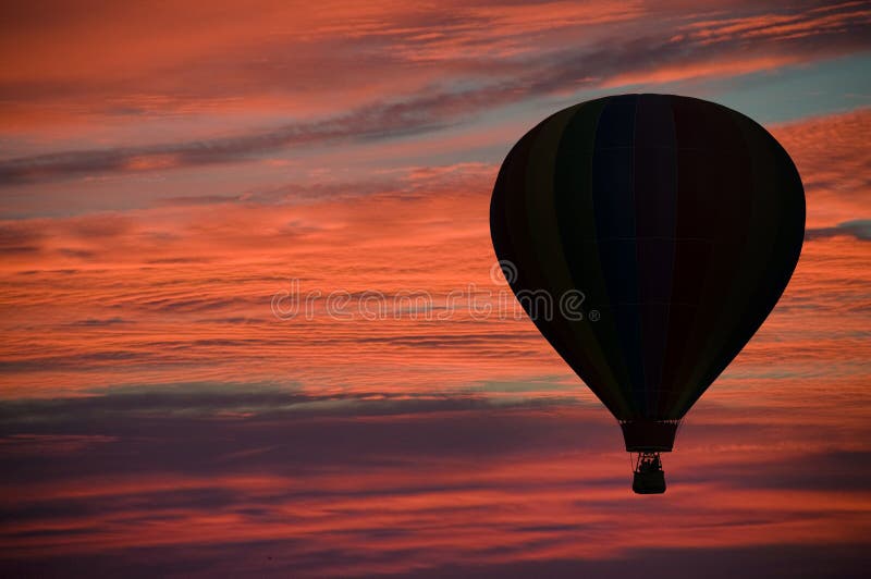 Hot-air ballooning among pink and orange clouds
