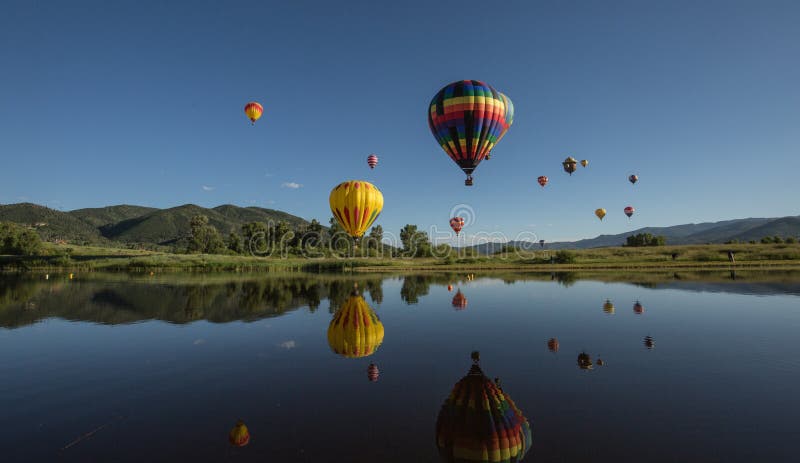 Colorful Hot Air balloons flying above lake in scenic mountains of Colorado