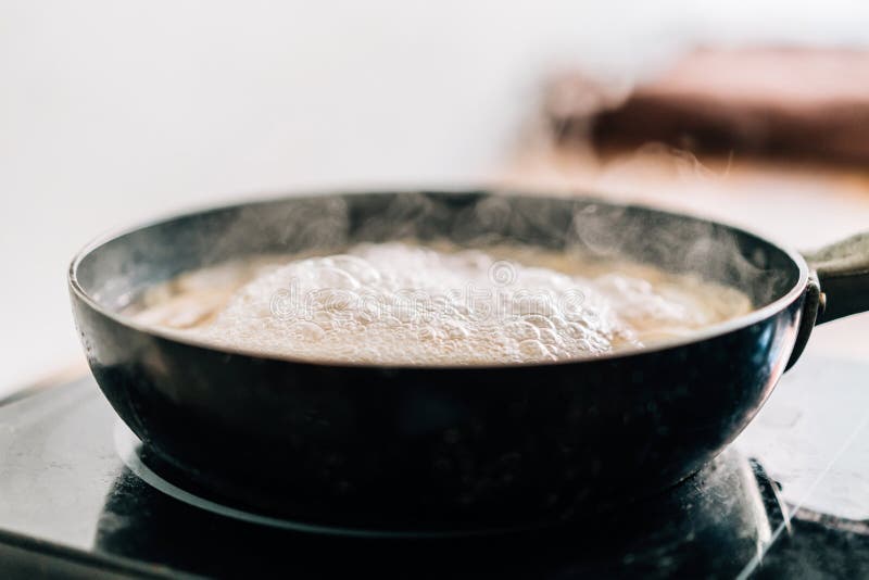 Hot Boiling Water in a Black Pan with Floating Steam. Boiling Water for