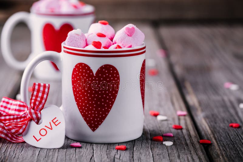 Hot cocoa with pink marshmallow in mugs with hearts for Valentine day