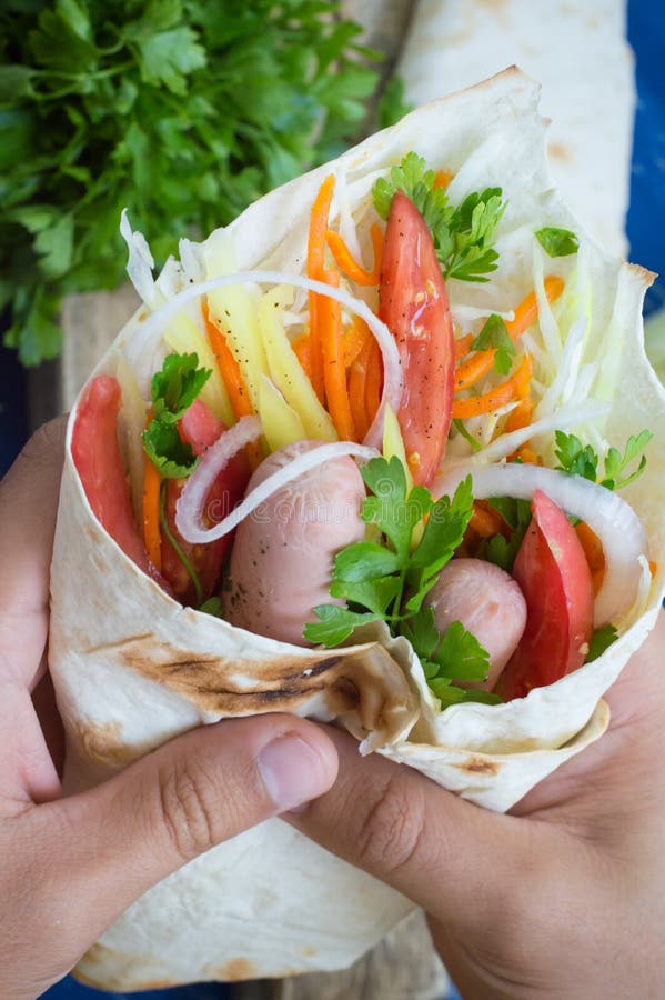 Hot dog a disposizione su peso - panino con la salsiccia in pita, carote coreane, pomodori, cipolle, prezzemolo e pepe Di legno fotografie stock Hot dog a disposizione su peso - panino con la salsiccia in pita, carote coreane, pomodori, cipolle, prezzemolo e pepe Di legno fotografie stock