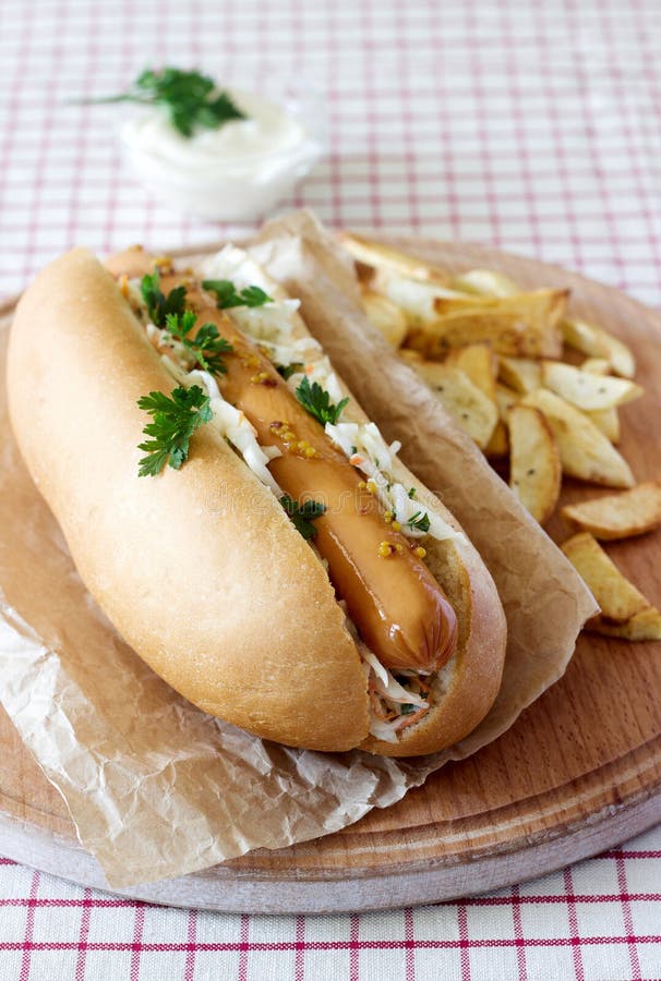Hot dog with sausage and salad, served with french fries, mustard and mayonnaise sauce. Rustic style, selective focus. stock photo Hot dog with sausage and salad, served with french fries, mustard and mayonnaise sauce. Rustic style, selective focus. stock photo