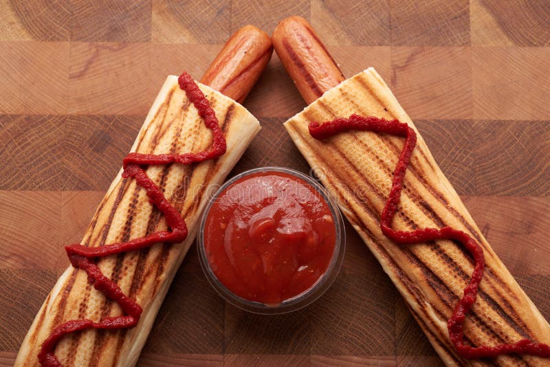 Two Hot Dogs and Tomato Sauce on a Wooden Tablet Top Stock Image