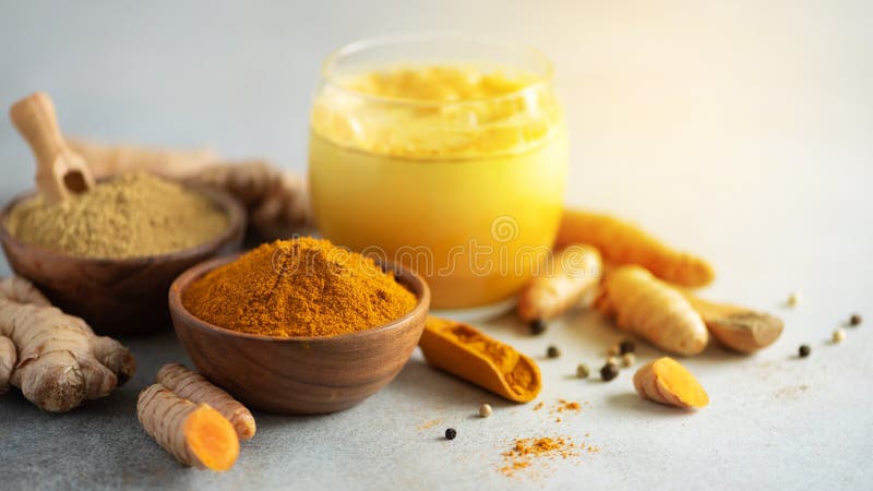 Hot healthy drink. Turmeric latte, golden milk with turmeric root, ginger powder, black pepper over grey background royalty free stock photography Hot healthy drink. Turmeric latte, golden milk with turmeric root, ginger powder, black pepper over grey background royalty free stock photography