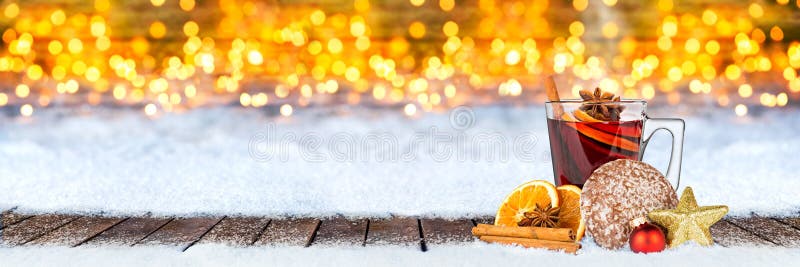 Hot mulled spiced red wine in glass mug with gingerbread orange