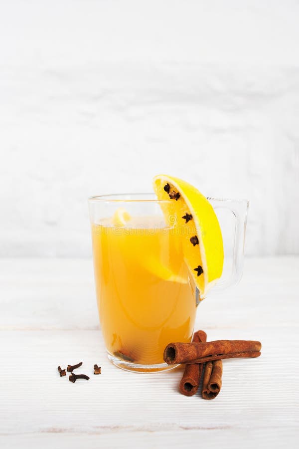 Hot orange juice in glass and spice on white