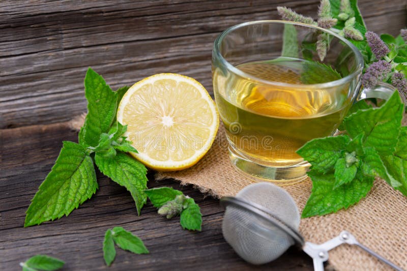 Hot peppermint tea with lemon on wooden background