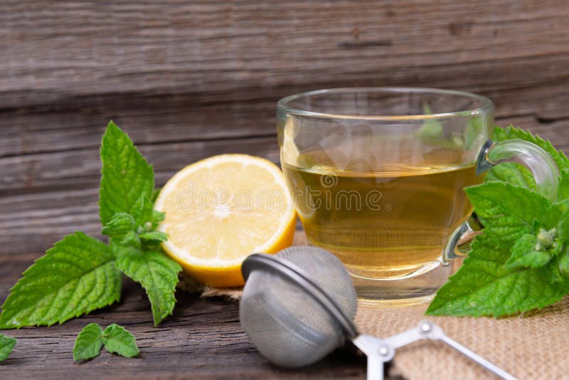 Hot peppermint tea with lemon on wooden background